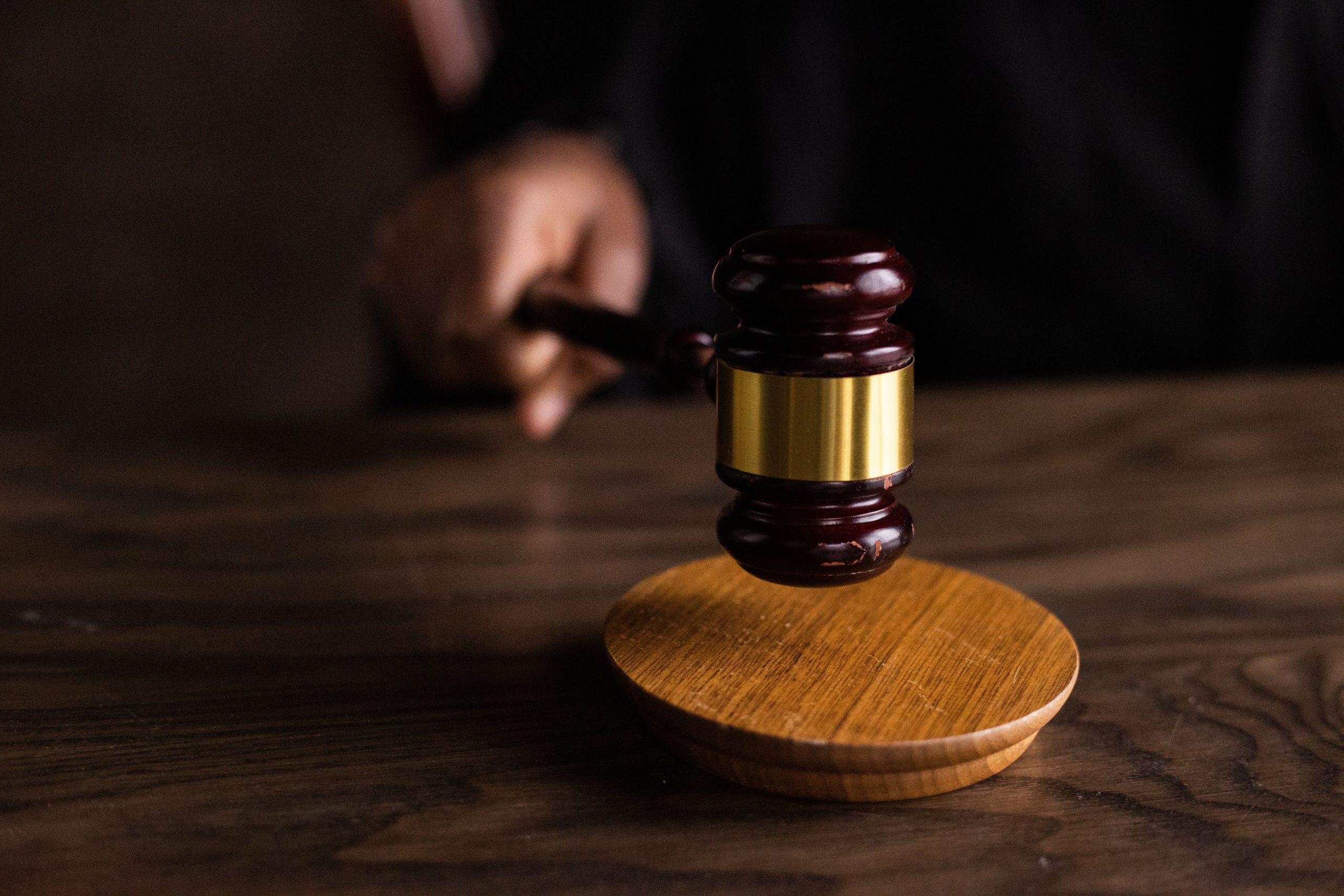 Home A gavel striking a sound block, symbolizing justice and legal authority in a courtroom setting.